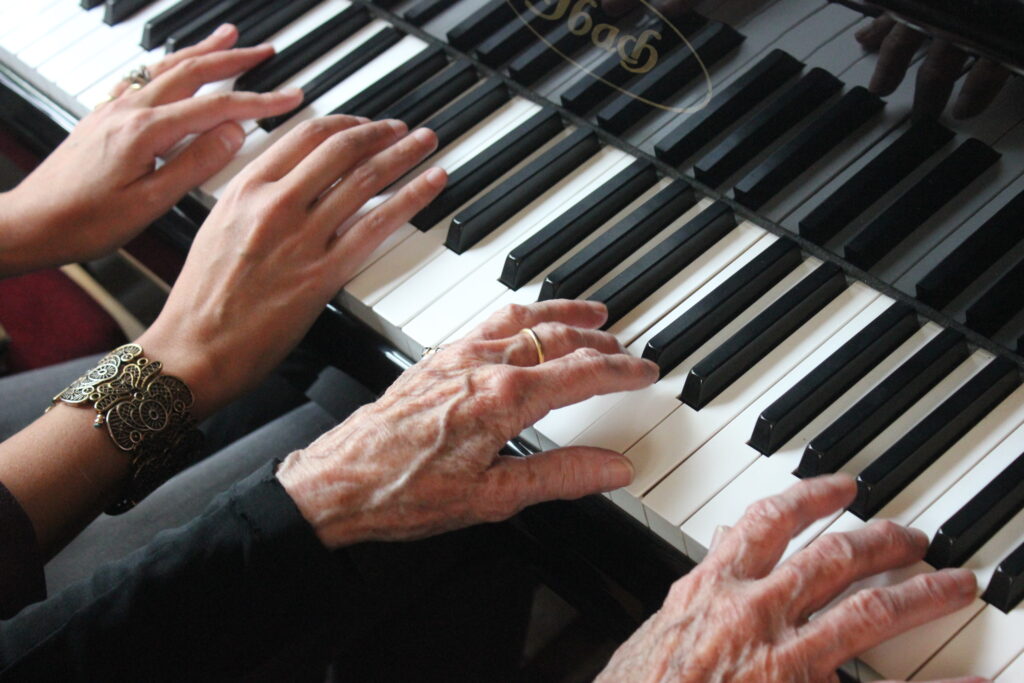 Zoom sur une personne âgée jouant au piano.